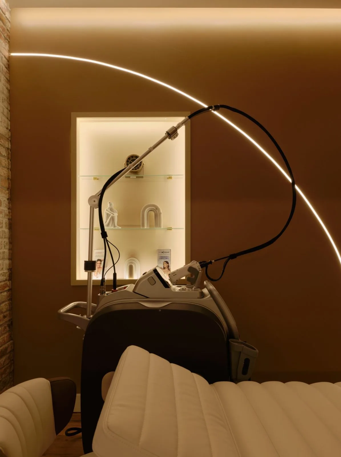 La Reservé Aesthetics treatment room with laser device mounted above treatment bed, illuminated neon accent lighting, and backlit shelving in West Village location